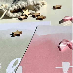 Geboortekaartjes met een houten sterretje en roze strikje.