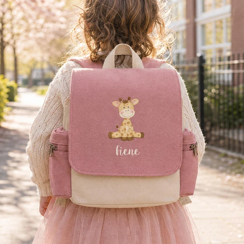 Roze kinderrugzak met naam en girafje op de rug van een meisje op weg naar school